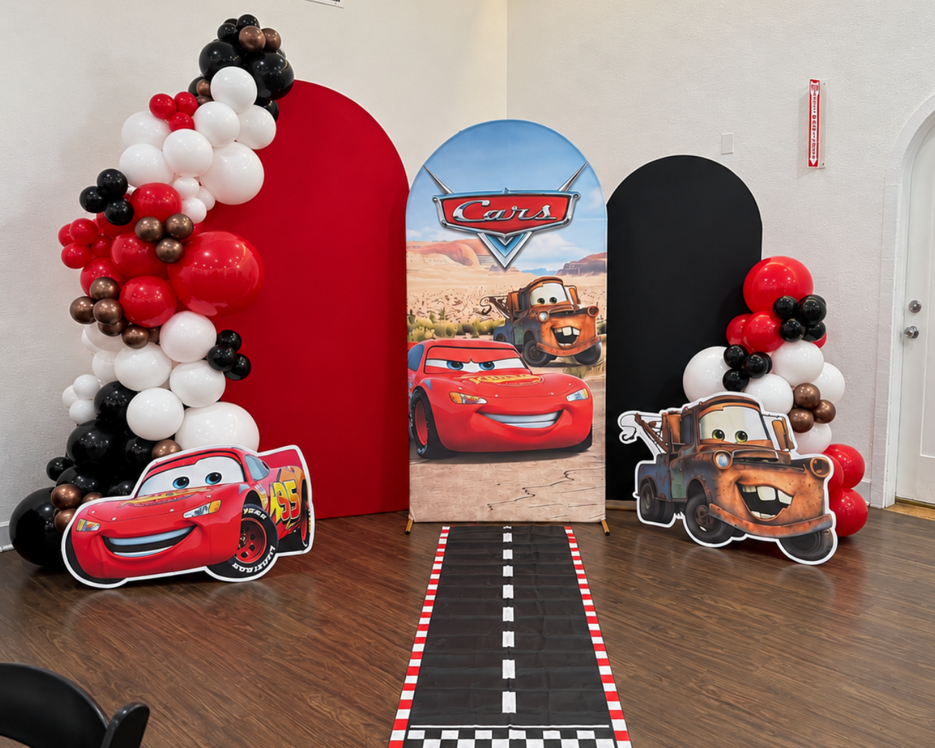 Cars themed party setup with balloon arches Lightning McQueen and Mater cutouts